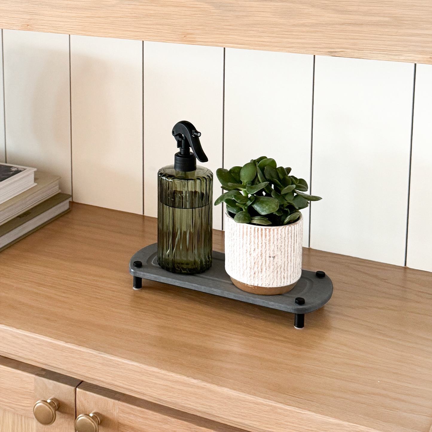 A white sink caddy is displayed on a wooden shelf with a ceramic decorative pot and a plant pot arranged on top.