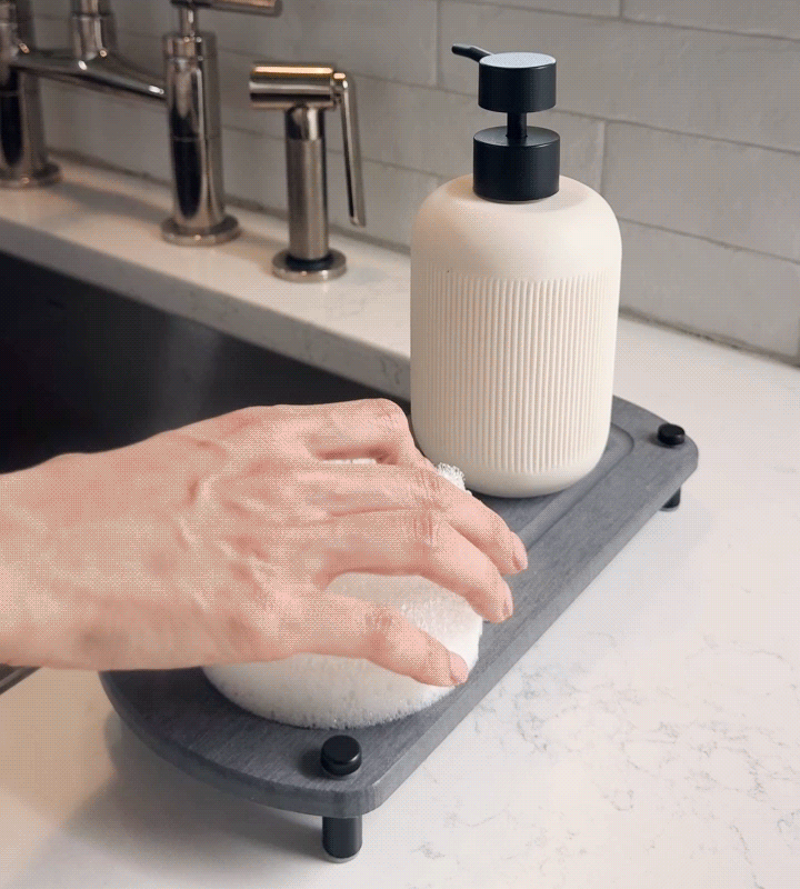 A GIF shows a woman's hand removing a sponge from a glacier gray sink caddy, with water evaporating instantly to showcase its fast drying performance.