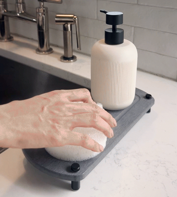 A GIF shows a woman's hand removing a sponge from a glacier gray sink caddy, with water evaporating instantly to showcase its fast drying performance.